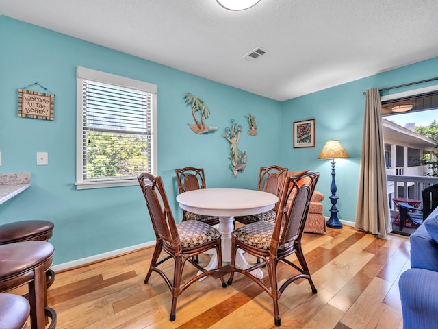 dining space with light hardwood / wood-style flooring and a textured ceiling