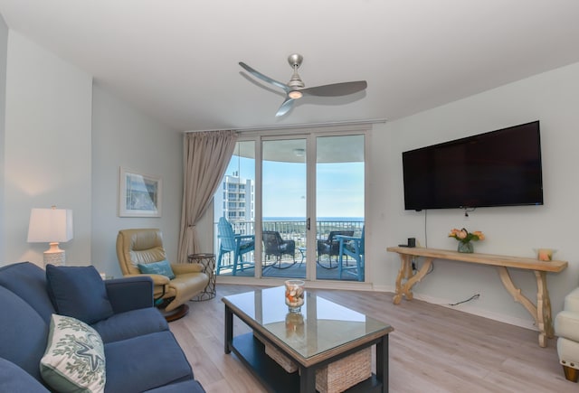 living area featuring light wood-type flooring, baseboards, and a ceiling fan