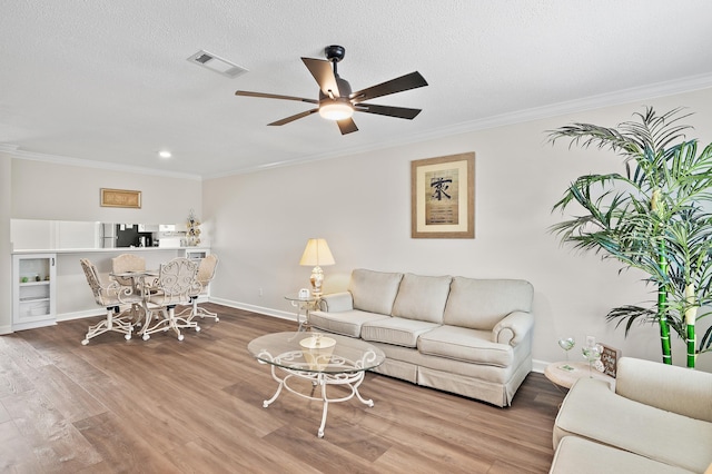 living room with a textured ceiling, hardwood / wood-style flooring, ceiling fan, and ornamental molding