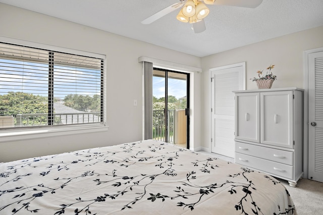 bedroom with ceiling fan, light colored carpet, a textured ceiling, access to outside, and a closet