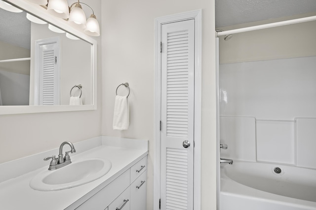 bathroom featuring shower / tub combination, vanity, and a textured ceiling