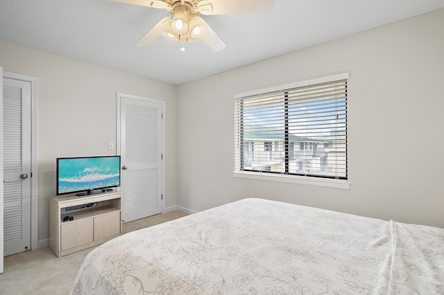 carpeted bedroom with multiple closets and ceiling fan