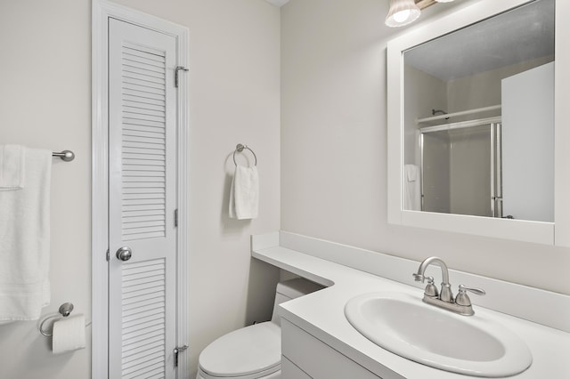 bathroom featuring vanity, toilet, and a shower with shower door