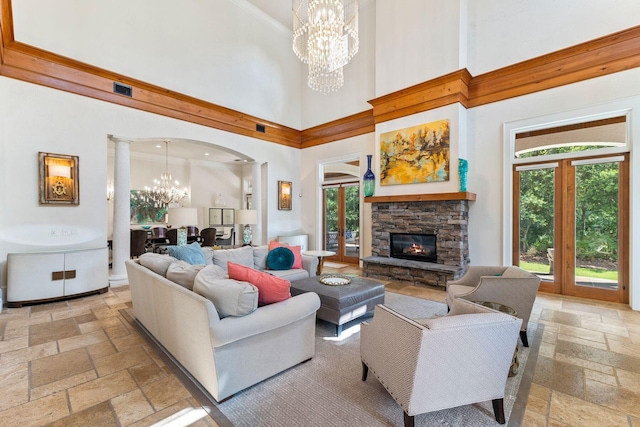 living area with arched walkways, a fireplace, an inviting chandelier, stone tile flooring, and crown molding