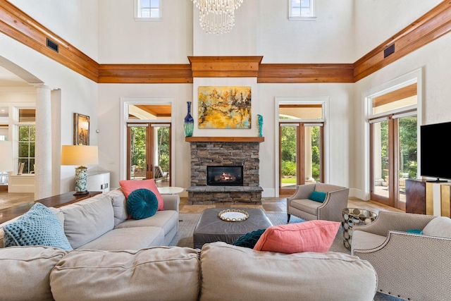 living room featuring decorative columns, a fireplace, visible vents, and a chandelier