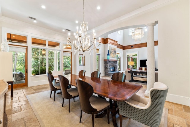 dining space with visible vents, a fireplace, stone tile floors, and an inviting chandelier