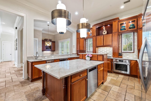 kitchen with appliances with stainless steel finishes, stone tile flooring, crown molding, and a kitchen island