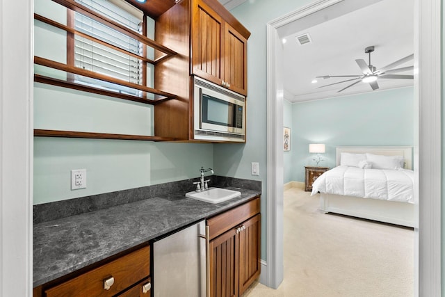 interior space featuring refrigerator, light carpet, a sink, brown cabinets, and stainless steel microwave