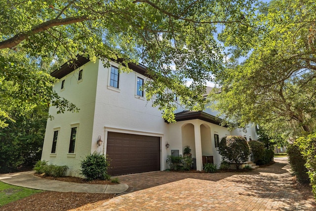 view of front of house featuring an attached garage, decorative driveway, and stucco siding