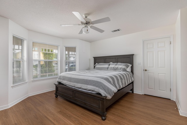 bedroom with dark wood-type flooring, ceiling fan, and a textured ceiling