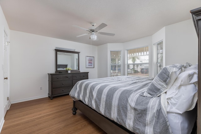 bedroom featuring ceiling fan, hardwood / wood-style floors, and a textured ceiling