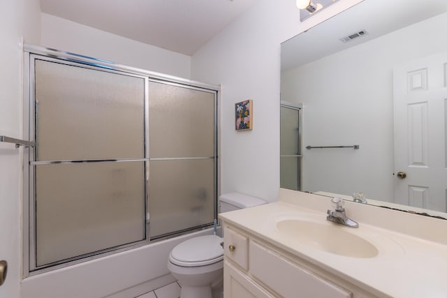 full bathroom featuring vanity, bath / shower combo with glass door, tile patterned floors, and toilet