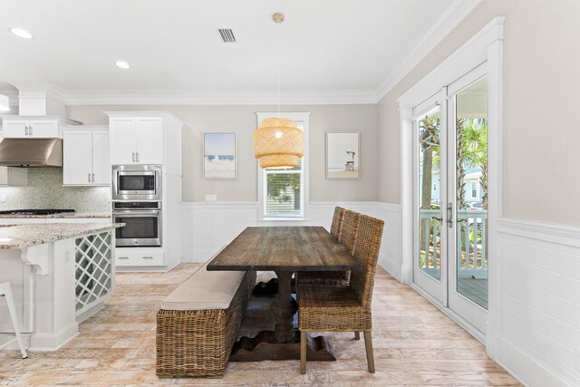 dining room with crown molding, plenty of natural light, and light wood-type flooring