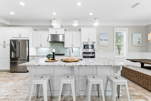 kitchen with pendant lighting, white cabinetry, a kitchen island with sink, light stone counters, and stainless steel appliances