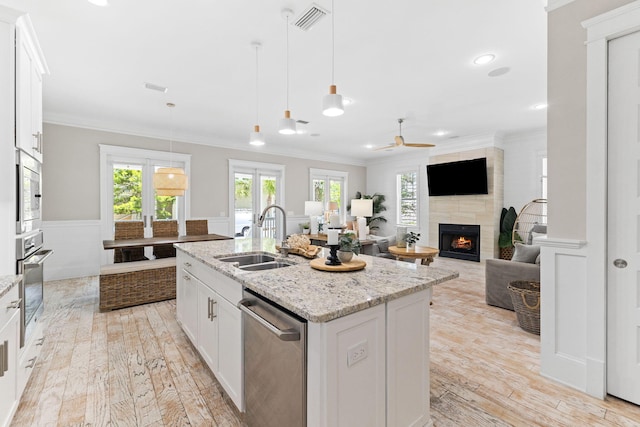 kitchen featuring sink, an island with sink, stainless steel appliances, light stone countertops, and white cabinets