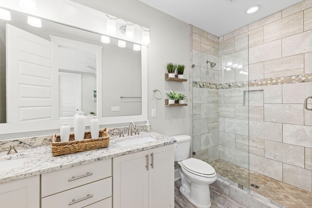 bathroom featuring vanity, a shower with door, and toilet