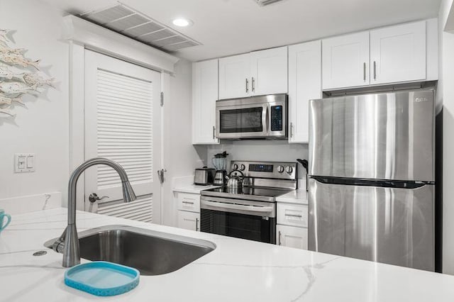 kitchen featuring white cabinetry, sink, light stone countertops, and appliances with stainless steel finishes