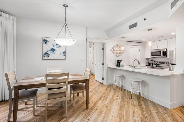 dining space with light wood-type flooring and sink