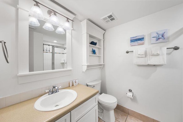 bathroom with tile patterned flooring, vanity, toilet, and a shower with shower door