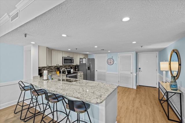 kitchen featuring stainless steel appliances, light hardwood / wood-style flooring, light stone counters, and kitchen peninsula