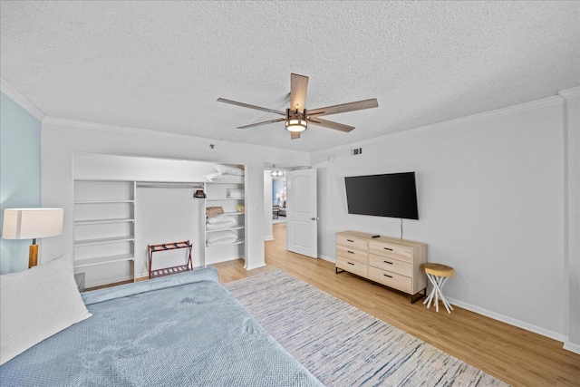 bedroom with hardwood / wood-style floors, ornamental molding, ceiling fan, a textured ceiling, and a closet