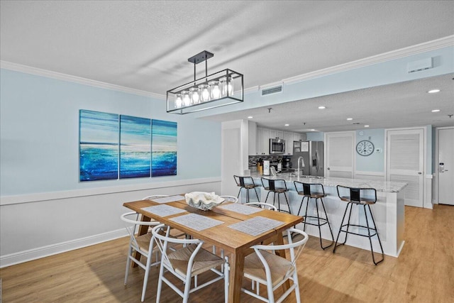dining area with crown molding, a textured ceiling, and light wood-type flooring
