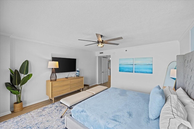 bedroom featuring ceiling fan, ornamental molding, wood-type flooring, and a textured ceiling