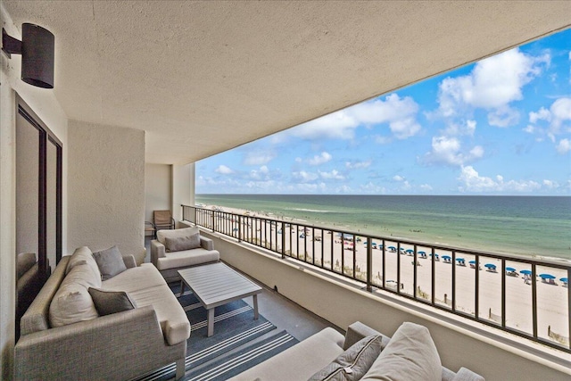 balcony with a view of the beach, an outdoor living space, and a water view