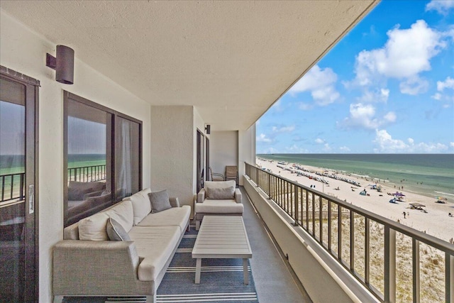balcony featuring a water view, outdoor lounge area, and a view of the beach