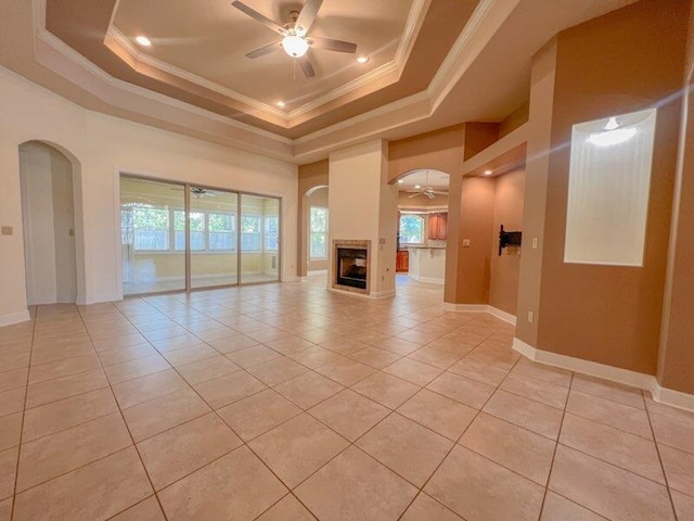 unfurnished living room featuring light tile patterned floors, a tray ceiling, ceiling fan, and crown molding