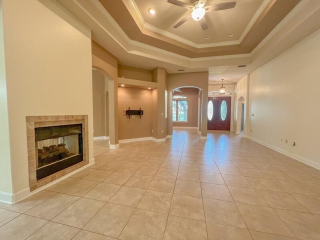 tiled foyer with a multi sided fireplace, a raised ceiling, ceiling fan, and crown molding