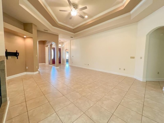 tiled empty room with a raised ceiling, ceiling fan, and crown molding