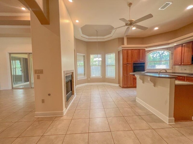 kitchen featuring ceiling fan, a kitchen bar, light tile patterned floors, and black oven