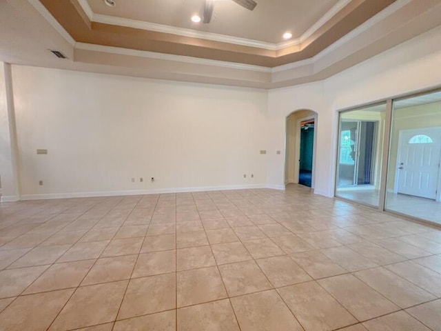 tiled empty room featuring ceiling fan, a raised ceiling, and ornamental molding