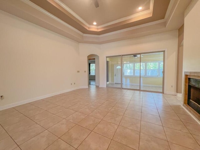 empty room with ceiling fan, crown molding, light tile patterned floors, and a fireplace