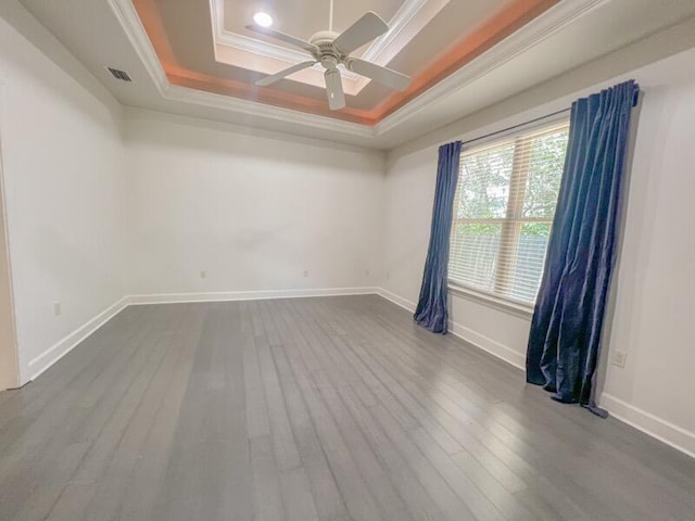 spare room featuring wood-type flooring, a tray ceiling, ceiling fan, and crown molding