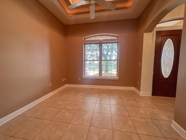 tiled entrance foyer with a raised ceiling and ceiling fan