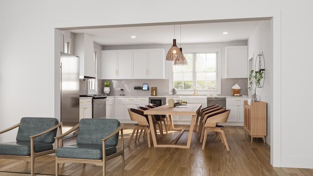 kitchen featuring pendant lighting, white cabinetry, hardwood / wood-style floors, stainless steel appliances, and decorative backsplash