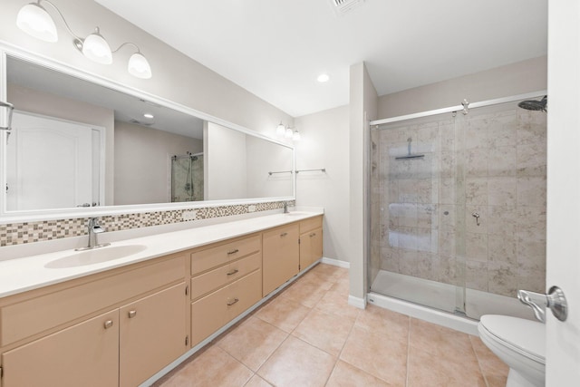 bathroom featuring a shower with shower door, tile flooring, double sink vanity, and toilet