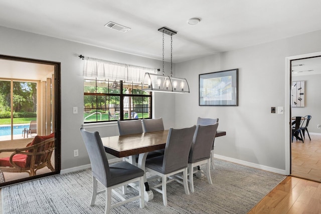 dining area with light hardwood / wood-style floors, a healthy amount of sunlight, and a chandelier