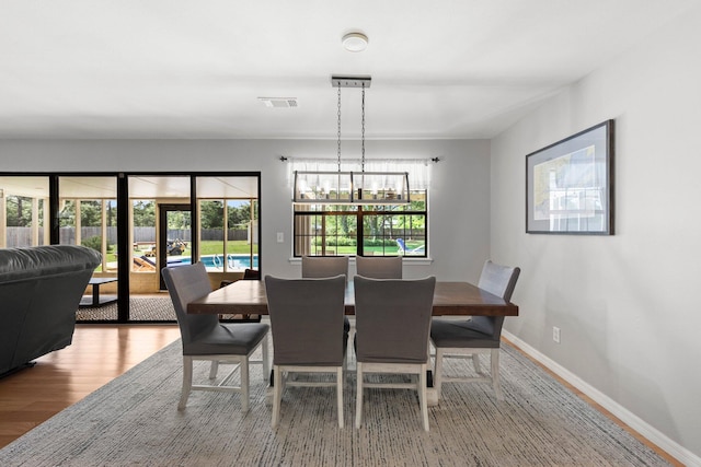 dining area featuring a healthy amount of sunlight, wood-type flooring, and a chandelier