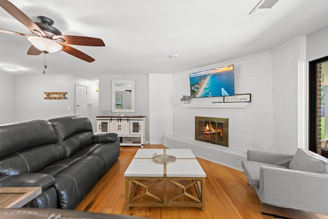 living room with a fireplace, ceiling fan, and light hardwood / wood-style flooring