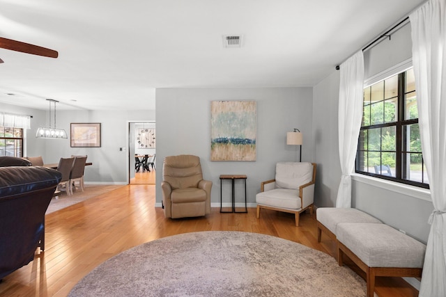 living room with hardwood / wood-style floors and ceiling fan with notable chandelier