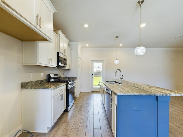 kitchen with appliances with stainless steel finishes, sink, a center island with sink, and decorative light fixtures