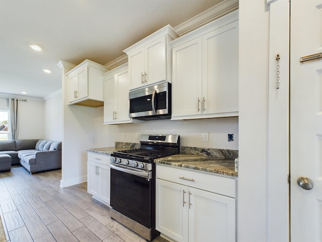 kitchen with appliances with stainless steel finishes, white cabinets, and dark stone counters