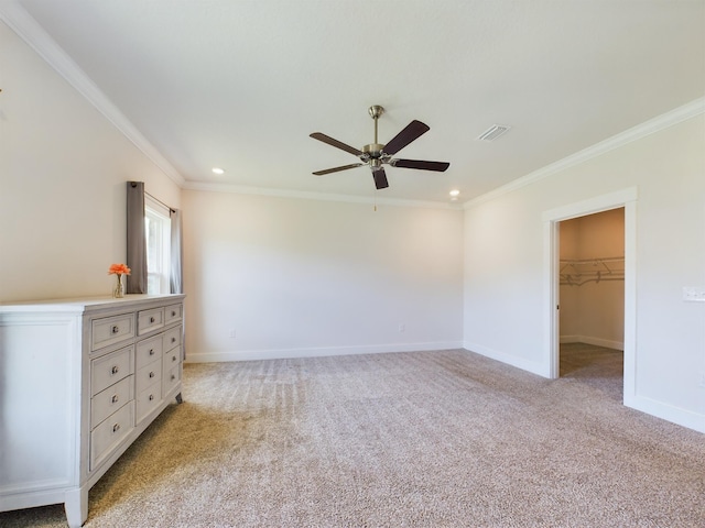 unfurnished bedroom featuring crown molding, a walk in closet, light carpet, a closet, and ceiling fan