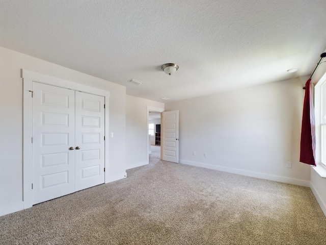 unfurnished bedroom featuring carpet floors, a closet, and a textured ceiling