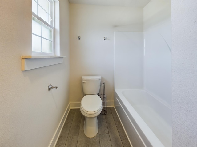 bathroom featuring a bathtub, hardwood / wood-style flooring, and toilet