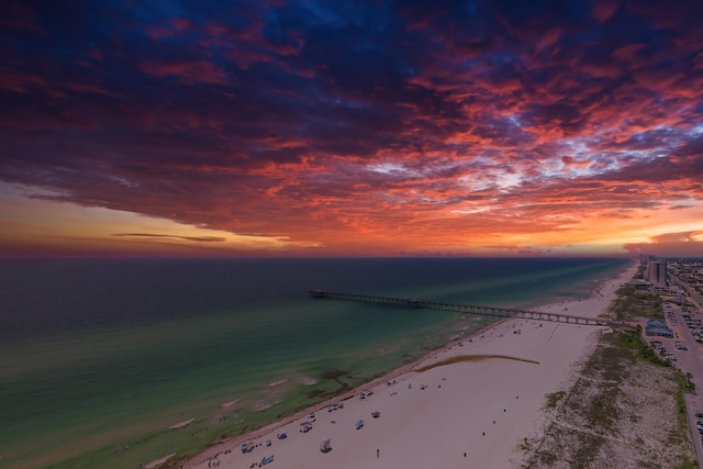 aerial view at dusk featuring a beach view and a water view