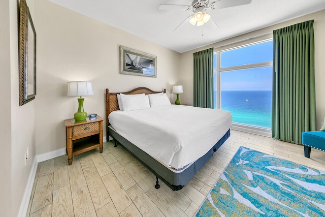 bedroom featuring ceiling fan, a water view, and hardwood / wood-style flooring